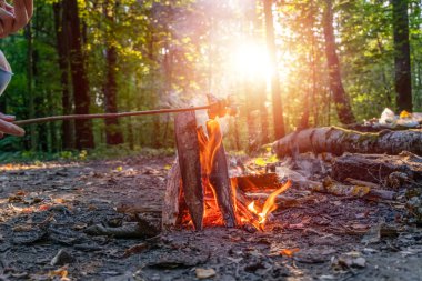 Gün batımında ormanda kamp yaparken kamp ateşinde kızarmış pastırma.