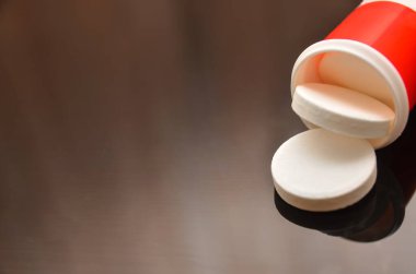 Siyah bir masanın üzerine kırmızı plastik bir şişeden dökülen coşkun bir C vitamini tabletini kapat. Sağlık ve güzellik kavramı için vitamin ve mineral takviyesi. Boşluğu kopyala