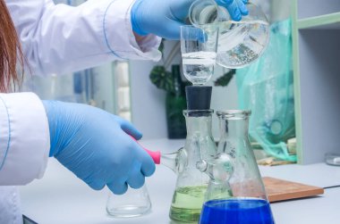 Bir kimyager elinde cam bir test tüpü tutar, sıvı çözeltiyi taşır, çeşitli reaksiyonlar kullanarak kimyasal reaktör seçenekleri kullanır..