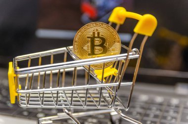 Sarı sepetteki altın bitcoin dizüstü bilgisayarın üstünde duruyor. Modern teknoloji kavramı