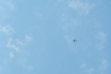 Profesyonel bir insansız hava aracı mavi gökyüzüne karşı alçaktan uçuyor. Drone fotoğraf çeker. Modern yeni teknoloji