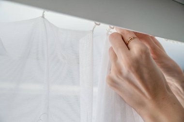 Kadın kapalı ya da kapalı, kapalı beyaz perdeleri kaldırır.