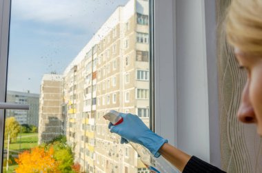 Güneşli bir sonbahar gününde pencereleri deterjan spreyiyle temizlemek