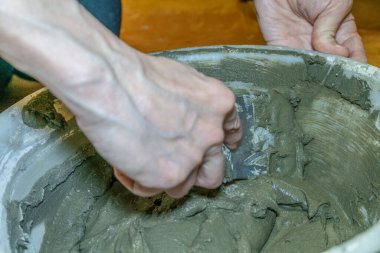 Kadın eli dairede kiremit döşemek için çimento harcı yoğuruyor. kovada çimento çözeltisi