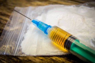 Bir torba uyuşturucu, ahşap arka planda yakın plan şırınga.