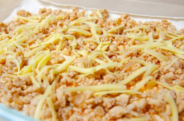 Pişirmek için cam bir kapta ev yapımı lazanya pişirmek. Fırına göndermeden önce peynirli lazanya serpiştirilmiş.