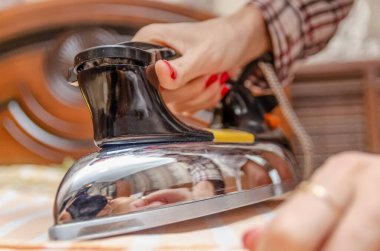 Kırmızı ojeli, eski ütülü, çizgili tişörtü olan bir kadının eli.