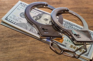 Kelepçe ve para ahşap masada. Dolar. hücum kavramı