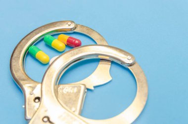 Mavi arka planda kelepçe ve haplar. Yakın plan.