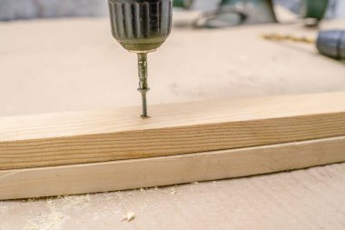 İşçi mobilya yapmak için tornavidayla delik açıyor.