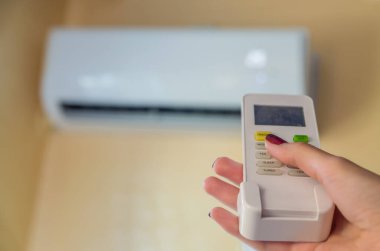 Oturma odasının arka planında klimayı tutan kadının görüntüsü.