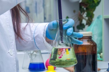 Kimyagerin elinde cam test tüpü taşar. Potasyum permanganatın sıvı çözeltisi bir analiz reaksiyonu oluşturur..