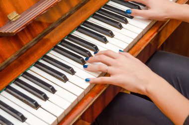 Piyanonun tuşlarına mavi tırnak cilası sürmüş kadın bir piyanistin elleri. Piyano çalan kız..