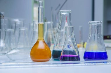 Masanın üzerinde çok renkli sıvı bulunan laboratuvar camları. Kimyasal analiz.
