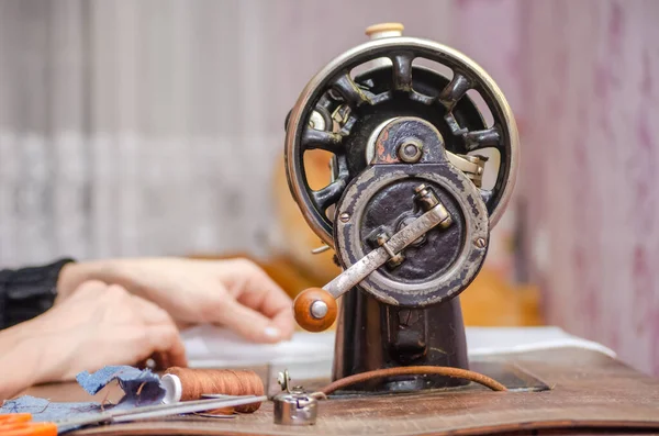 Eski bir dikiş makinesinde çalışan bir kadın. Eller yakın plan.