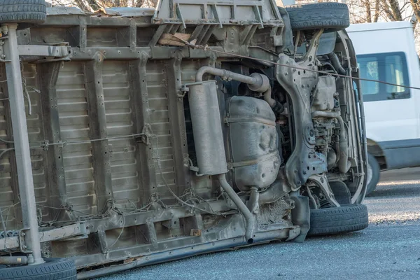 Ters dönmüş bir araba minibüsü yolda yan yatarken, arabanın dibi kameraya bakar. Alt ters dönmüş araba minibüsü yakın plan.