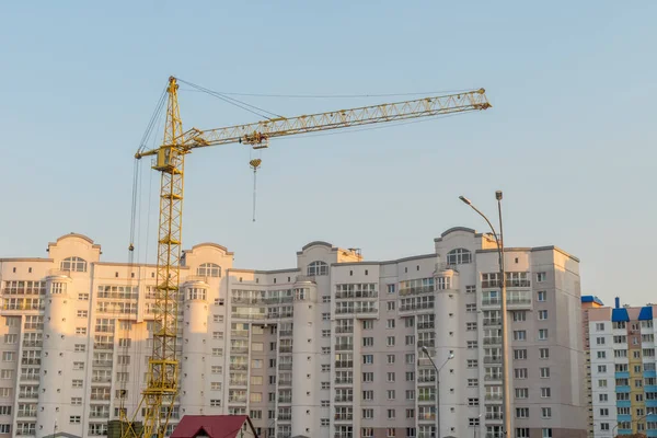 Sarı kule vinci ve açık mavi gökyüzüne karşı çok katlı bir bina.