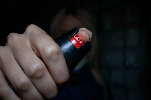 Blonde woman holding pepper spray for self defense close up