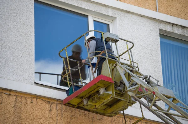 man on crane cleaning the window