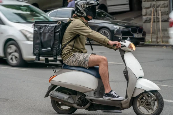 Kurýr Batohem Zádech Bílém Skútru Doručením Jídla Ulici — Stock fotografie