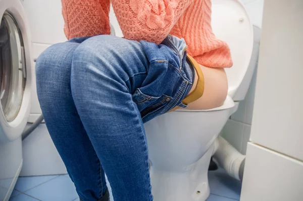 Kobieta Zaparciami Lub Biegunką Siedzi Toalecie Niebieskich Dżinsach Nogach — Zdjęcie stockowe