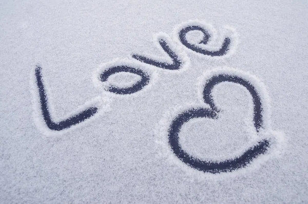 Writing text LOVE on the snow, painted heart on snow