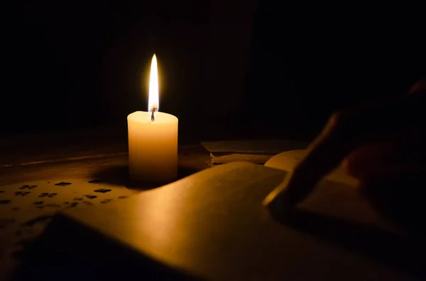 Cards, a book, a candle, a hand on a wooden table. study of magic. concept of divination, magic.