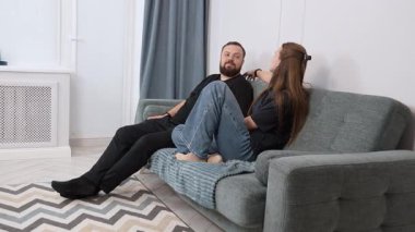 Middle-aged couple sitting closely on comfortable living room sofa, sharing warm conversation and intimate connection, radiating peaceful domestic atmosphere during relaxing weekend moment