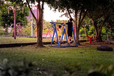 Alacakaranlıkta bir oyun alanında oynayan iki kardeş..