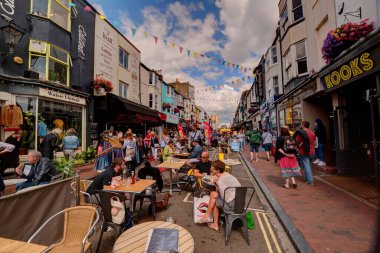Brighton, Birleşik Krallık - 25 Ağustos 2018: İnsanlar Brighton, İngiltere 'de masalarda otururken sokakta yiyip içiyorlar ve oradan geçen turist ve müşterilerle birlikte