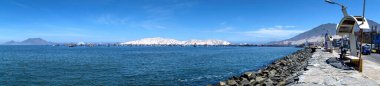 Chimbote, Peru - April 10, 2018: Panorama of sea front showing coastal defences and numerous moored trawlers with islands in the background clipart
