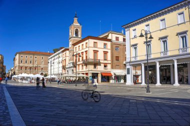 Rimini, İtalya - 20 Ekim 2019: Piazza Tre Martiri Meydanı 'ndaki pazar ve kilise bazı hareketler yayaları ve müşterileri bulanıklaştırdı.