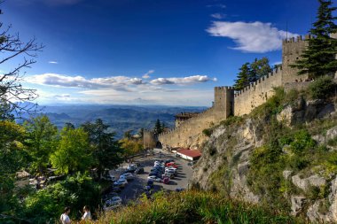 San Marino, San Marino - 19 Ekim 2019: Araçlar ve turistlerle dolu Guaita Kulesi 'nin taş duvarının altındaki otopark