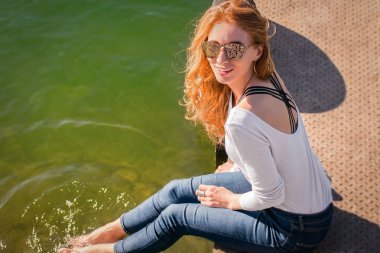 Kızıl saçlı kız Rıhtımlar üzerinde oturur