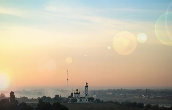 De stralen van de dageraad zon over de stad en de ochtend mist — Stockfoto