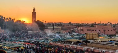 Fas'ı gezi. Gün batımında Koutoubia Camii ve Jemaa el-Fnaa pazar meydanı, Marakeş, Fas