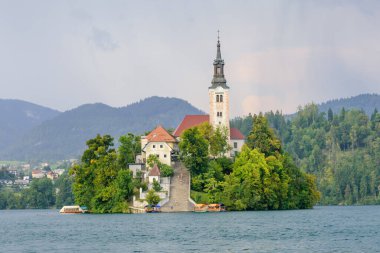 Küçük adadaki St. Marys Varsayım Kilisesi ile kan gölü. Kan, Slovenya, Avrupa. Arka planda dağlar ve vadiler. 