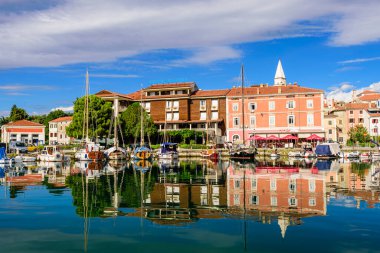 Izola, Slovenya - 20 Eylül 2016: Izola rıhtımında tekneleri ve parlak renkli evleri olan manzaralı liman.