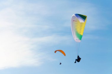Gündüz mavi gökyüzünde uçan paraşütler 