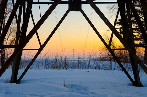 Elektrik pilon karla kaplı manzaraya aracılığıyla günbatımında görüntülemek