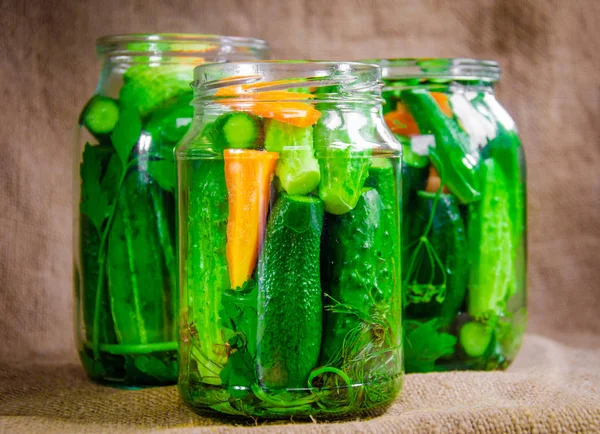 Arka planda cam kavanozlarda konserve salatalıklar.