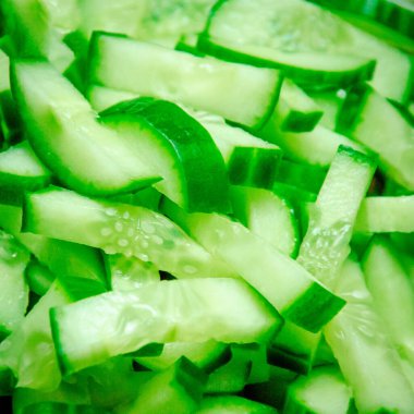 Yeşil çiğ salatalık, ahşap bir rafta büyük bir bıçakla ince ince doğranmış.