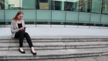İş kadını merdivenlerde oturuyor ve cep telefonu kullanıyor. Yüksek kalite 4k görüntü