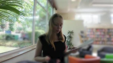 Kütüphanede broşürlere bakan genç bir kadın. Yüksek kalite 4k görüntü