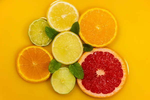 Çeşitli narenciye ve nane yapraklarıyla merkez kompozisyon. Portakal suyu arkaplanı.