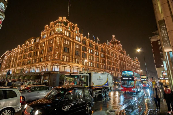 夜の交通とロンドンのハロッズデパートの近くにイギリスで典型的な雨の日の通りの風景 ロンドン イギリスの冬の間の夜の都市シーン — ストック写真