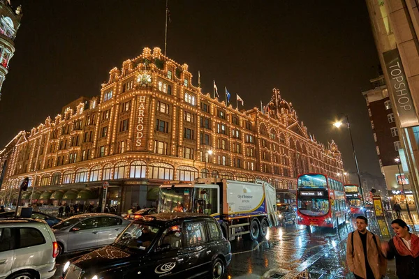 夜の交通とロンドンのハロッズデパートの近くにイギリスで典型的な雨の日の通りの風景 ロンドン イギリスの冬の間の夜の都市シーン — ストック写真