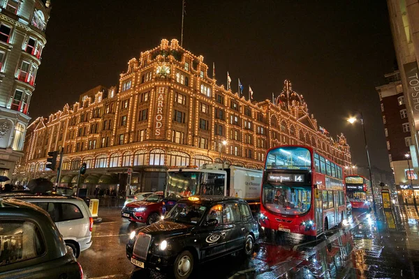 夜の交通とロンドンのハロッズデパートの近くにイギリスで典型的な雨の日の通りの風景 ロンドン イギリスの冬の間の夜の都市シーン — ストック写真