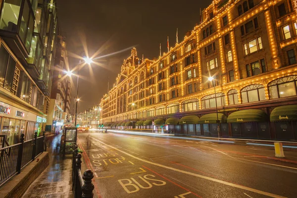 夜の交通とロンドンのハロッズデパートの近くにイギリスで典型的な雨の日の通りの風景 ロンドン イギリスの冬の間の夜の都市シーン — ストック写真