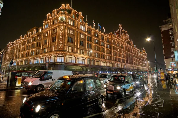 夜の交通とロンドンのハロッズデパートの近くにイギリスで典型的な雨の日の通りの風景 ロンドン イギリスの冬の間の夜の都市シーン — ストック写真